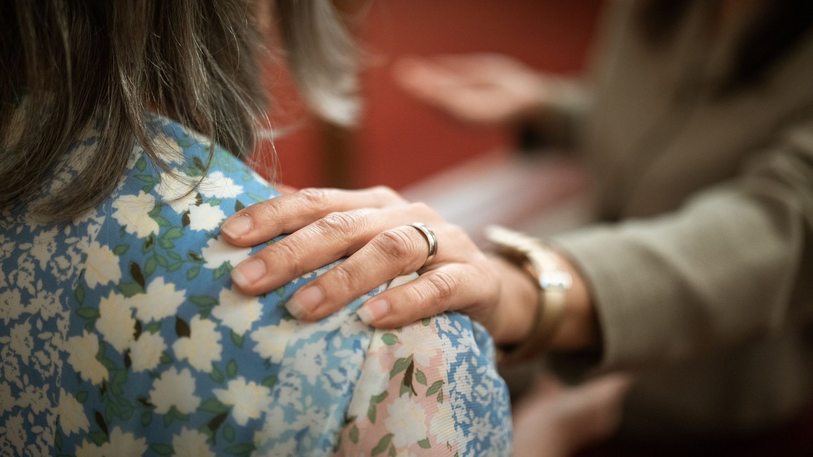 A comforting hand resting on someone's shoulder, illustrating the presence at the heart of compassion.