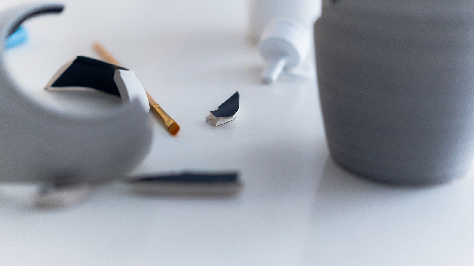 Broken ceramic being carefully mended, echoing the Japanese art of kintsugi and the resilience of repair.