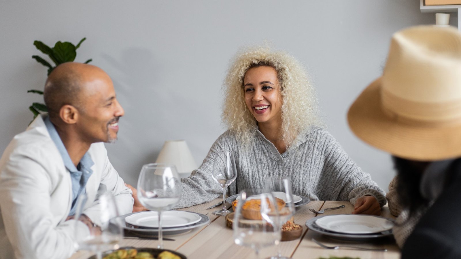 Friends talking and laughing over a shared meal at a sunlit table.