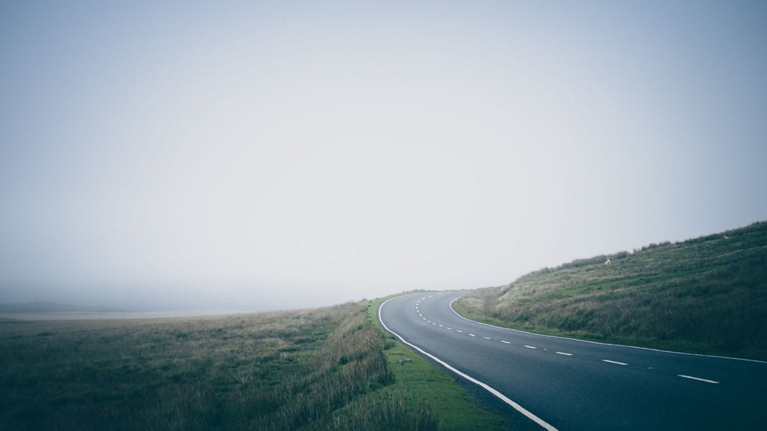 An open road curving into morning mist, illustrating adventure as stepping toward the unknown.