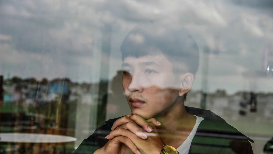 A young man behind a window with the sky reflected over him, illustrating self-reflection and living with integrity.