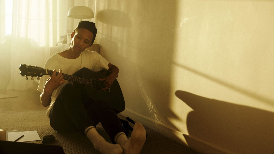 A young man absorbed in playing acoustic guitar in golden light, illustrating the aliveness of following a passion.