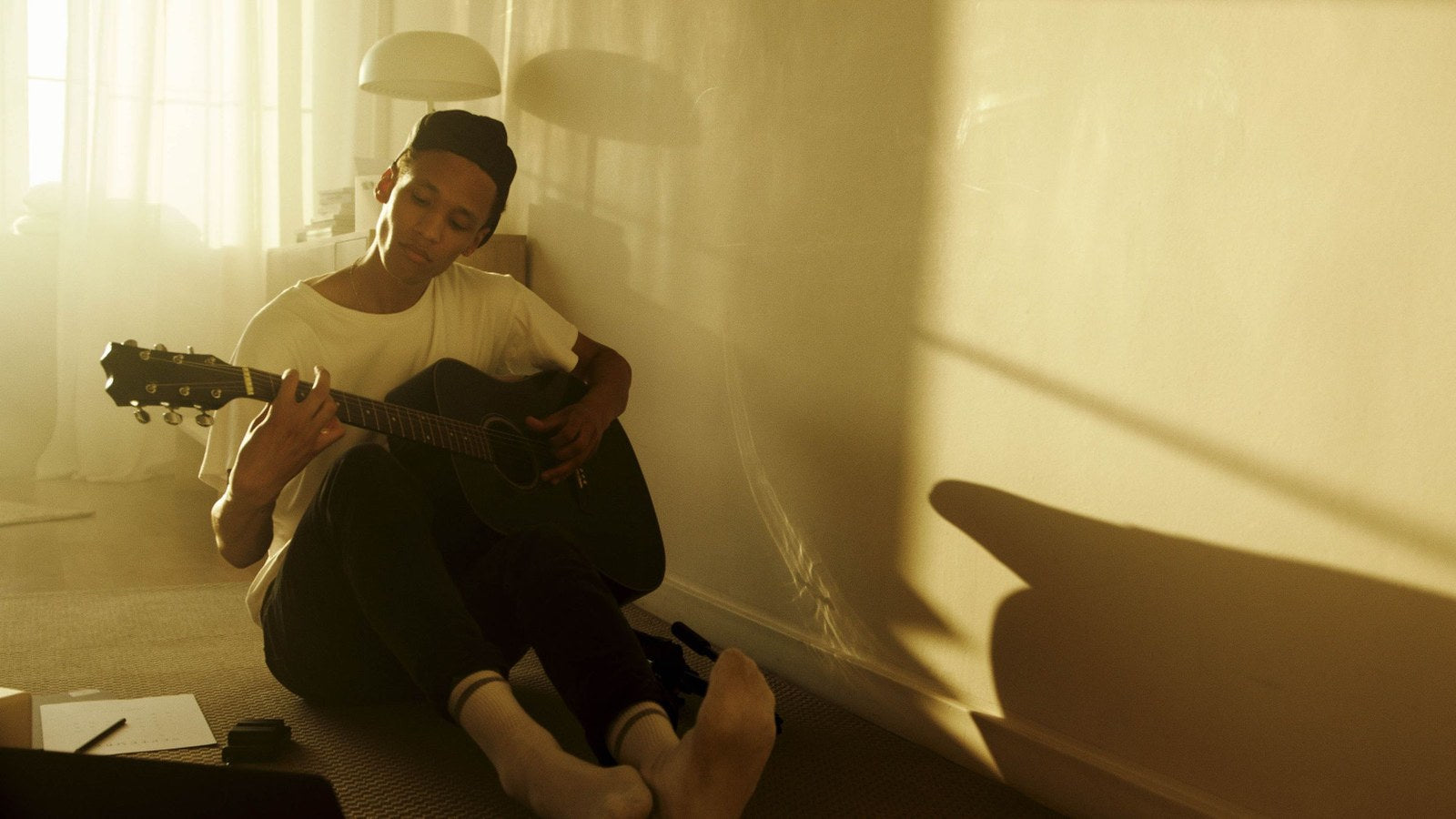 A young man absorbed in playing acoustic guitar in golden light, illustrating the aliveness of following a passion.